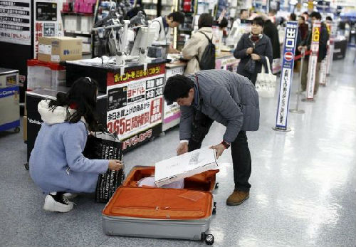 中国游客赴日“爆买”引发热议。图为中国游客在东京一家商场中购物后装箱。