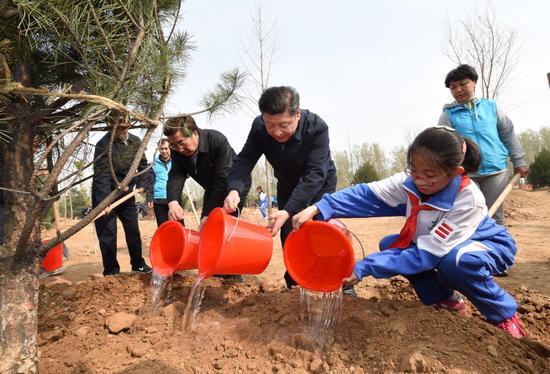 这是习近平同大家一起给刚栽下的树苗浇水。