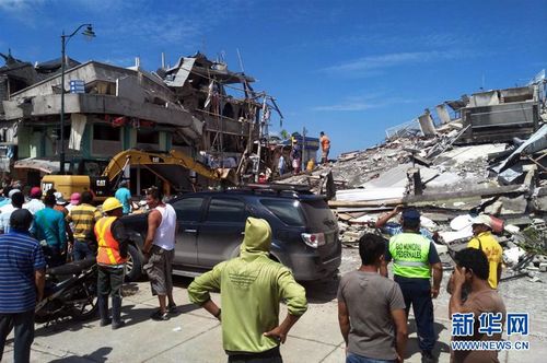 4月17日，在厄瓜多尔乔内市，当地居民站在被地震毁坏的房屋前。新华社发
