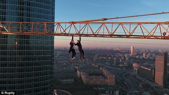两名俄罗斯小伙子在无任何保护措施下单手悬挂在高达几百英尺的机械臂上。（网站截图）