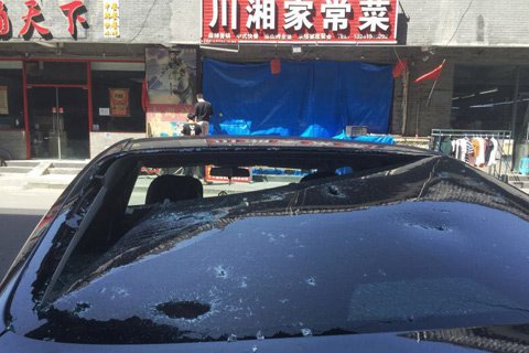发生爆炸的饭店，大门用蓝色塑料布遮挡，门口停的一辆黑色轿车，后窗玻璃被炸飞的饭店玻璃门砸伤。新京报记者 尹亚飞 摄