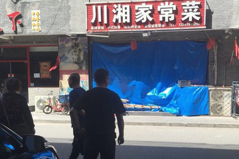 发生爆炸的饭店，大门用蓝色塑料布遮挡，门口数名男子看护，不许拍照。新京报记者 尹亚飞 摄