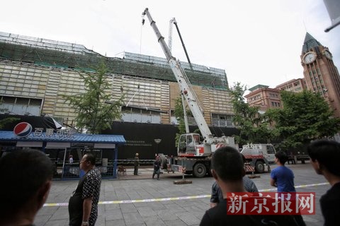 施工人员将砸落在饮品店的钢筋吊回工地内。新京报记者 彭子洋 摄