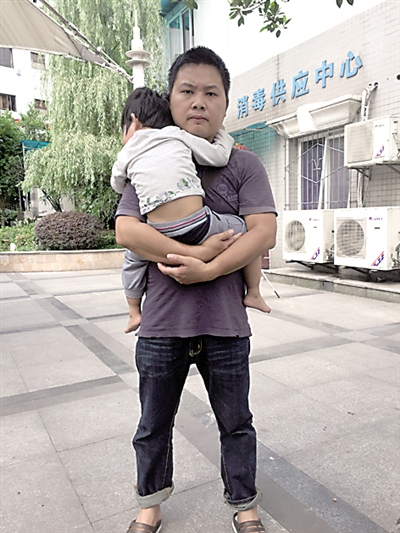 蓝广蓬抱着2岁的女儿，无助地站在医院门口。
