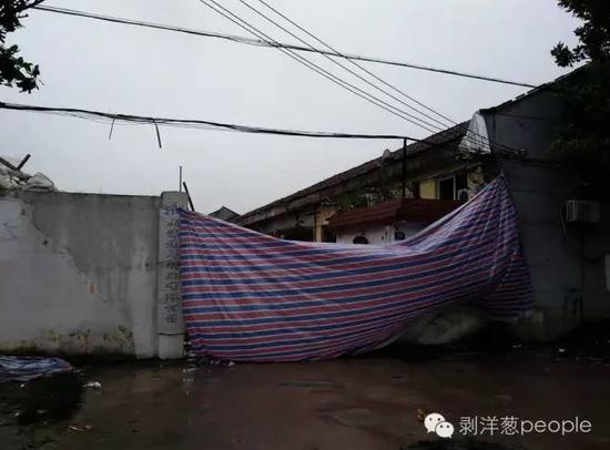 事发企业大门，事发后，有人用彩条布将大门遮住，其内一片狼藉。新京报记者谷岳飞 摄
