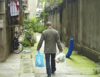 成都某中学外的小区内,一家长用中午空闲时间给住在这里的孩子买菜做饭。