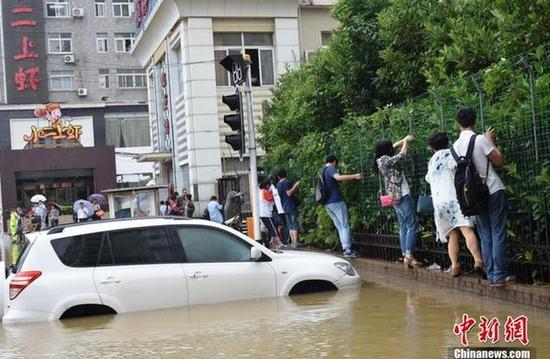 6月1日凌晨3时至上午10时，武汉市出现大到暴雨天气。据当地水务部门消息称，降雨中心位于江南地段，其中洪山、光谷地段降雨量达97-115毫米左右，全市20处地段出现渍水，多处道路被淹，不少轿车被困。目前，相关部门正组织抢排。图为渍水导致民众出行不便。 马芙蓉 摄