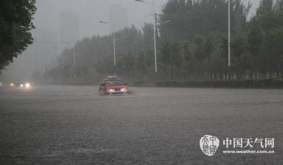 11日上午9时左右，沈阳乌云密布，大雨倾盆而下，道路瞬间被积水淹没，车辆涉水前行。（图/马东雷）