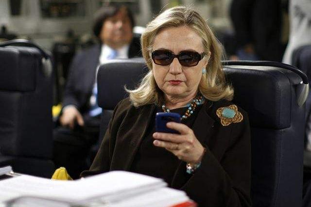 2011年10月18日，美国国务卿希拉里在飞往利比亚首都的黎波里的军用运输机上查看手机信息。（图片来源：新华/美联）
