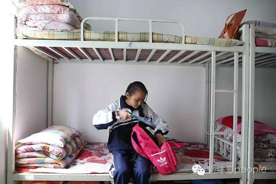2016年4月25日，居仁中学，彭晓敏正在宿舍收拾东西。留守儿童在学校的食宿都是免费的。