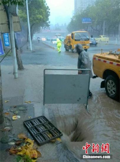 图为武汉鹦鹉大道朝阳路口段，水务工人揭盖排水。 钟欣 摄  