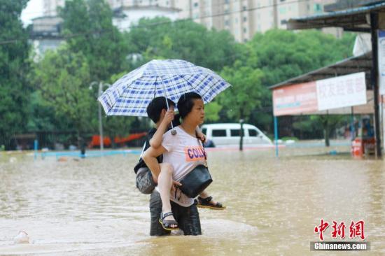 6月19日，市民冒雨在江西省景德镇市珠山区新厂街道景华小区积水路段涉水出行。中新社发 程万海 摄 图片来源：CNSPHOTO