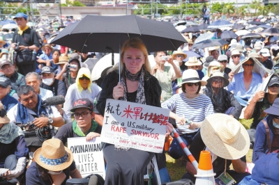6月19日，在日本冲绳，一名抗议者手举“我是美军暴行受害者”的标语。新华社发