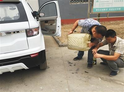 上图代步车生产公司，两名工人正在给一辆将要装车发货的燃油车加油。