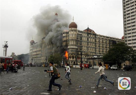 2008年11月29日，在印度孟买的泰姬玛哈酒店附近，摄影记者在印度军警与恐怖分子交火时转移。新华社/路透