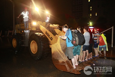 7月6日夜里，在武汉光谷大道金融港，现场积水最深处可达1米，来往居民通过需要靠铲车摆渡通行。昊哥摄