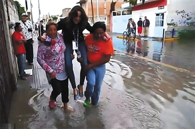 洪水灾区，两名居民抬着一名女记者。

