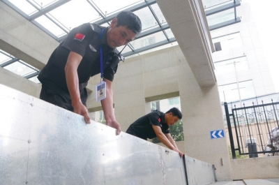 7月8日,在温岭市万昌中路附近的一个小区门口,物业工作人员正在安装“防洪神器”。 网络图片
