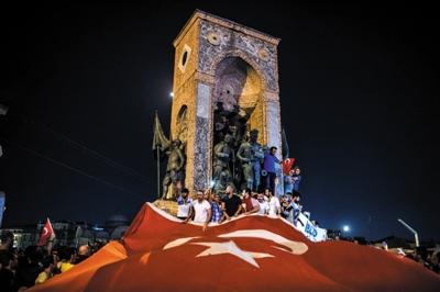 当地时间2016年7月16日，土耳其伊斯坦布尔，人们在塔克西姆广场挥舞巨幅国旗。土耳其总理耶尔德勒姆7月15日晚说，土耳其武装部队总参谋部部分军官当天企图发动军事政变。图/视觉中国