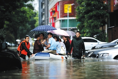 7月6日，武汉市武昌惠民路，由于积水过深，消防官兵用橡皮艇载着市民进行转移。图/视觉中国