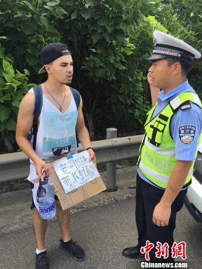 7月20日，一名俄罗斯小伙子手持“老司机请带我去福州”纸牌在高速上拦车，被执勤的泉州高速交警支队民警劝阻。　泉州高速 供图　摄