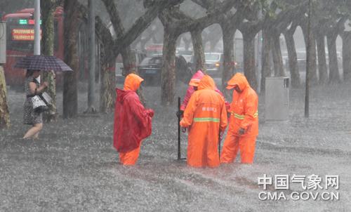 图为环卫工人为加速排水，站在打开的井盖前保护行人安全。