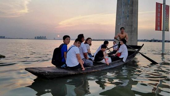7月8日,武汉江夏大道被水淹没,与周围的汤逊湖连为一体,附近居民坐船回家。 摄影:俞琴