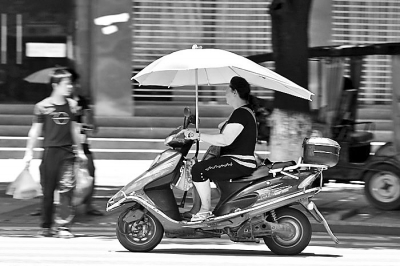 在很多城市的街头，随处可见擅自安装遮阳伞的电动车或摩托车。资料图片