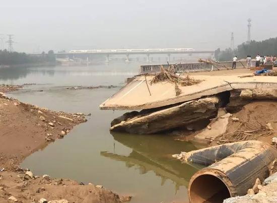 已被冲毁的七里河龙王大桥，远处是疾驰而过的动车 （《财经》记者 白兆东 摄 ）