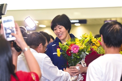 昨日，中国女排主教练郎平（中）在里约国际机场接受“粉丝”的鲜花。新华社记者 岳月伟 摄