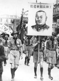 　　1938年5月9日，湖北汉口，战地服务童子军高举王铭章将军的遗像，引导阵亡英雄的花圈灵车。 （资料图片）