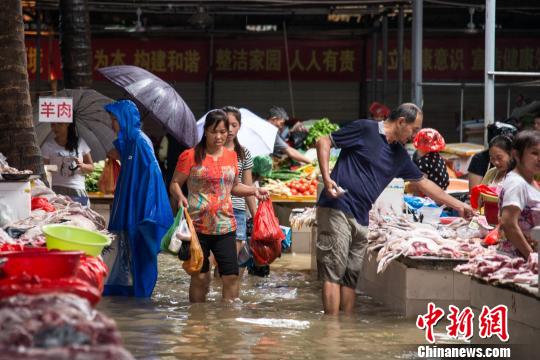 　　海口城市内涝，市民在积水的农贸市场采购。　洪坚鹏 摄