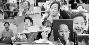 2015年，韩国民众举着原“慰安妇”的照片，在首尔日本大使馆外集会。