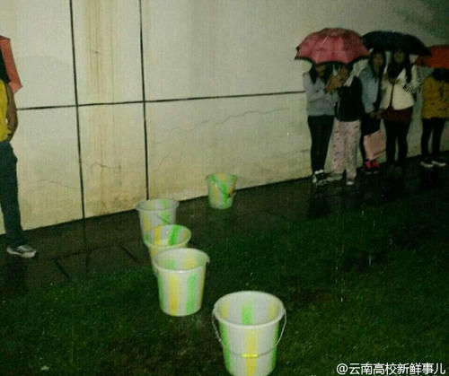 图为学生拿桶接雨水。