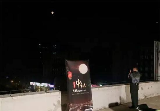 军事摄影家季文才在“北京时间”演播厅顶楼拍摄北京中秋夜晚的月亮 摄影：实习生 韩其臻