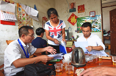 8月30日，在村民梁欲妹的家里，伍思扬律师（左1）在翻阅核对案卷资料。信息时报记者 陈引 通讯员 刘洪群 摄