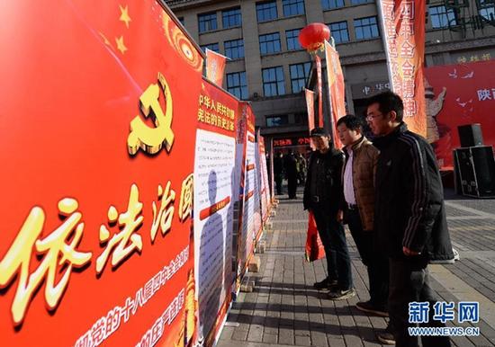 2014年12月4日，西安市民在宪法日宣传活动现场观看依法治国宣传展板。