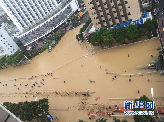 福州火车站南广场前“沦陷”。一早，工作人员到现场搭建临时桥，供行人出行。（图/新华网）