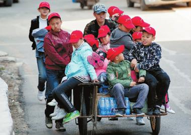 浩南（骑车者）带着孩子们去卖旧物 新文化记者 蒋盛松 摄