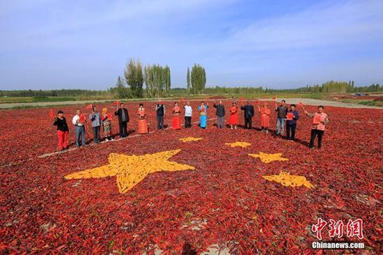 9月29日，新疆博湖县才坎诺尔乡农牧民团聚在一起，用辣椒、玉米等拼成一副别样壮美的五星红旗，喜迎祖国67周年华诞。来源：中新网
