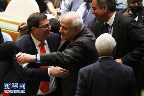 10月26日，在位于纽约的联合国总部，巴勒斯坦常驻联合国观察员曼苏尔（中）祝贺古巴外长罗德里格斯（左）。