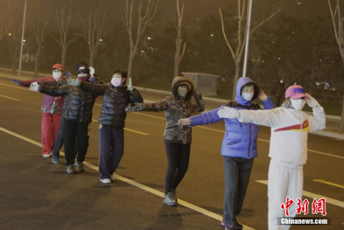 2015年12月8日晚,北京大妈无惧雾霾天,宁愿戴口罩,也要坚持跳广场舞。中新社记者 李慧思 摄