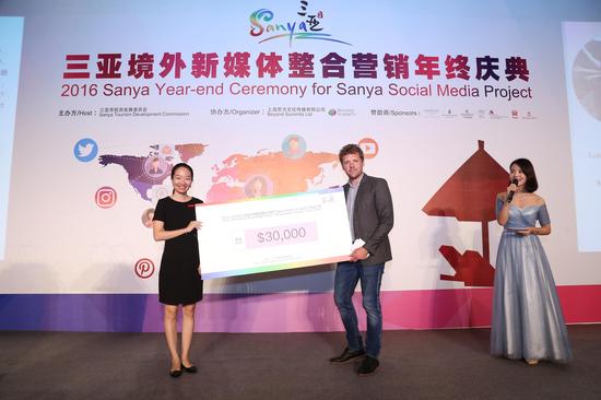 三亚市旅游发展委员会副主任王菲菲女士为3万美金现金大奖获得者Luke Campbell Charny颁奖。