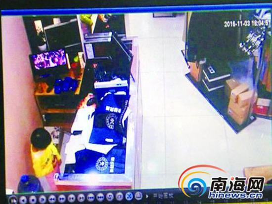 在店主招呼其他顾客之际,女孩钻进收银台,偷走了店主的苹果手机。