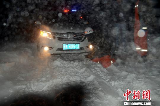 图为消防人员跪在雪地里用铁锹铲雪救援被困车辆。 李江江 摄