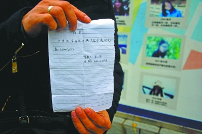 图为一位家长展示老师的借款条。记者杨涛 摄