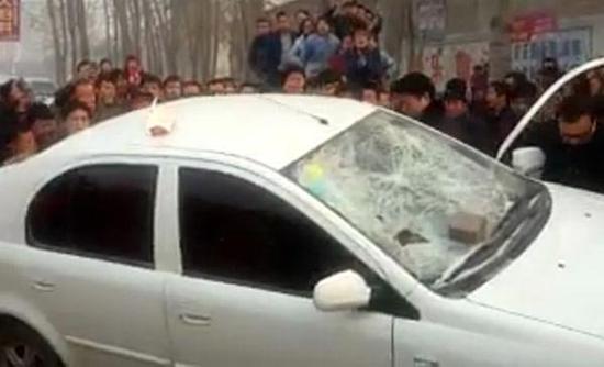 网传视频截图：众村民掀翻白色轿车。