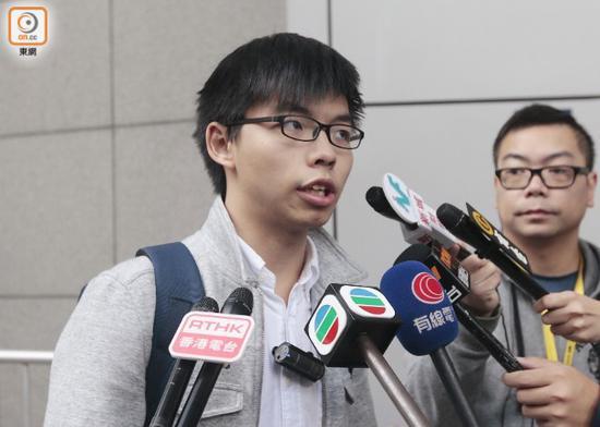 “香港众志”秘书长黄之锋在香港警察总部外向媒体传话/来源:东网