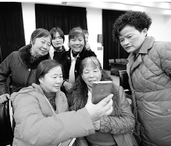赵玲巧（前左）如今也已当外婆，拿出手机跟孩子们视频聊天。