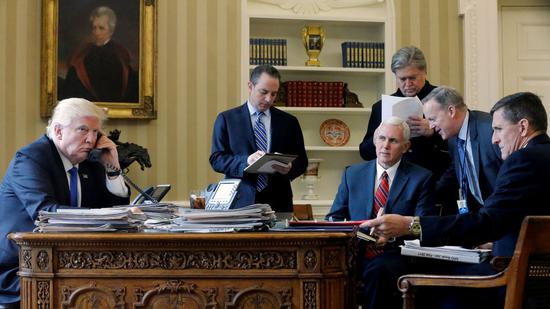 特朗普在椭圆形办公室与俄罗斯总统普京通电话，围绕在他身旁的是（左二起）白宫幕僚长普里伯斯、副总统彭斯（坐者）、高级顾问班农、白宫新闻秘书斯派塞和国家安全顾问弗林